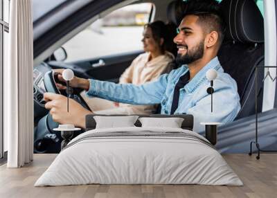 leisure, road trip, travel, family and people concept. Young happy indian man and woman driving in car Wall mural